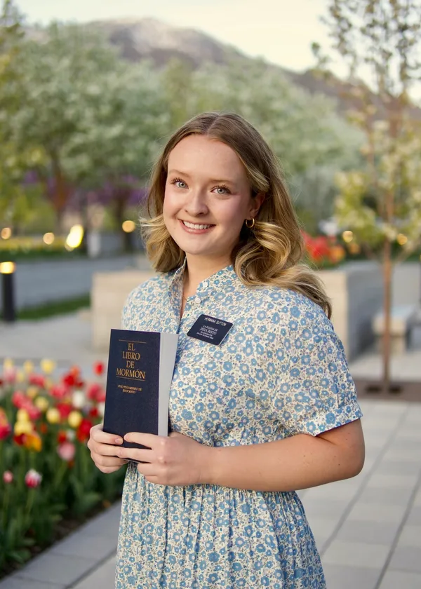 Young woman missionary smiling outdoors with pink blossoms and tulips in the background